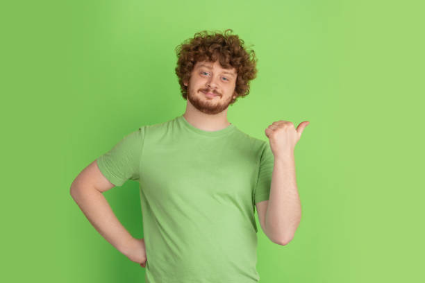 istock Caucasian young man's monochrome portrait on green studio background 1217779377