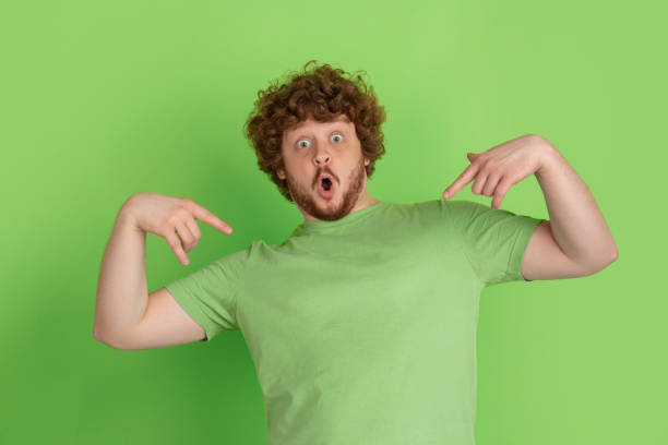 istock Caucasian young man's monochrome portrait on green studio background 1217779397
