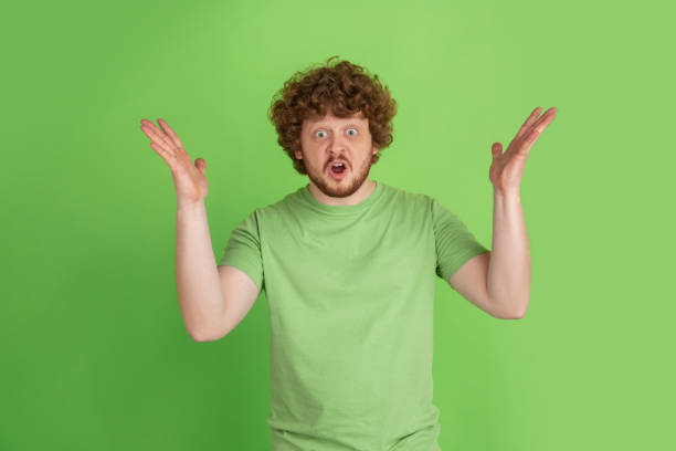 istock Caucasian young man's monochrome portrait on green studio background 1217779406