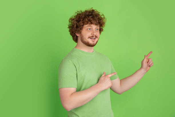 istock Caucasian young man's monochrome portrait on green studio background 1217779420