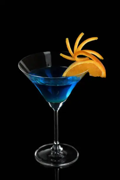 Decoration for a cocktail of orange. Elegant and original presentation. Martini Blue Curacao on a black background