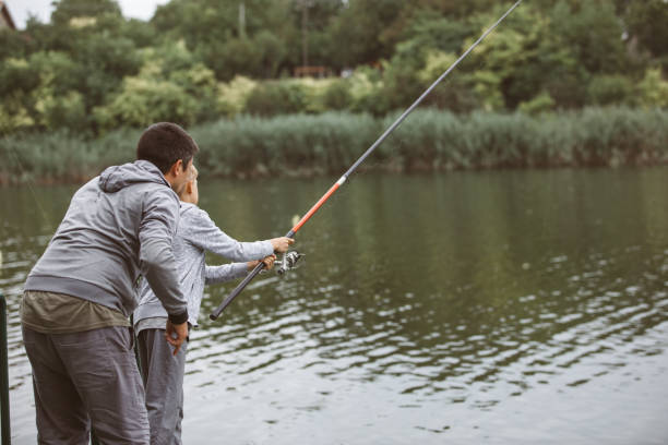 istock Committed man teaching boy how to use a fishing rod 1217784550