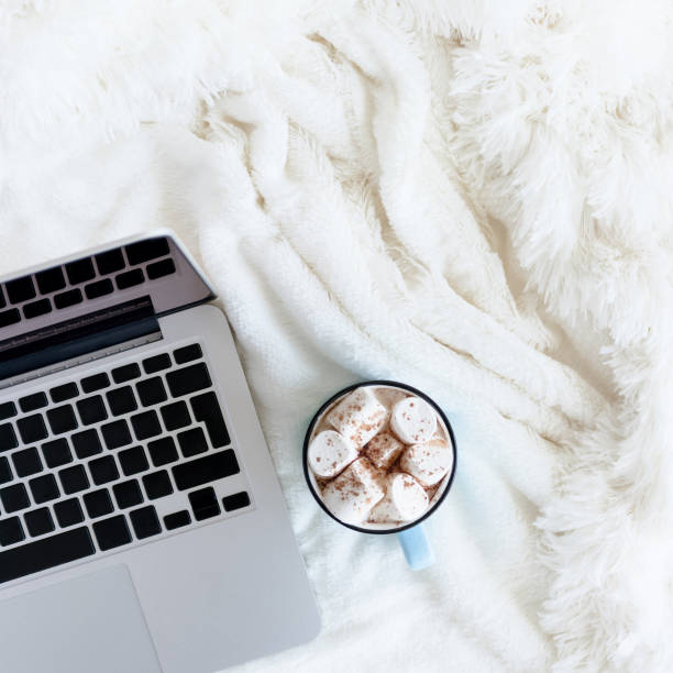 Composition with laptop and mug of cocoa with marshmallows.