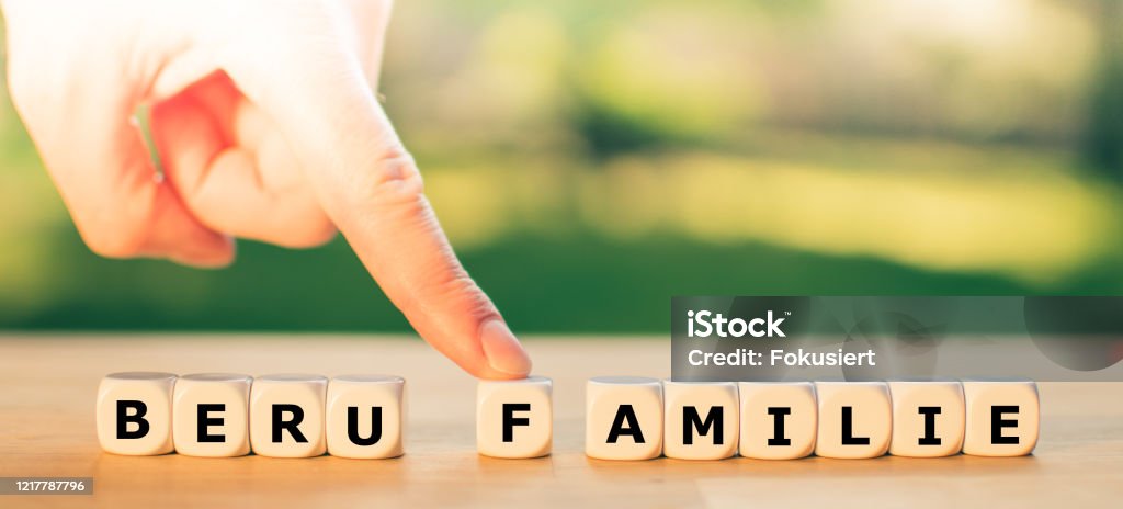 Work or family? A finger pushes the letter F away from the German word "Beruf" ("work") towards the word "Familie" ("family"). A symbol for work life balance. Occupation Stock Photo