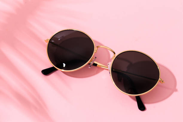 istock round shape black sunglasses on pink background with tropical leaf shadow 1217790636