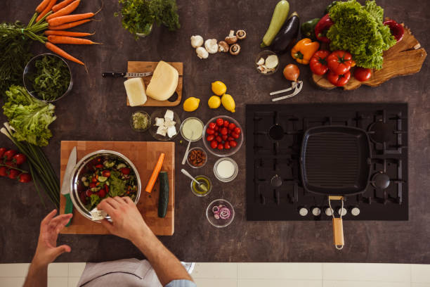 istock Man adding seasoning into a salad he is making 1217796384