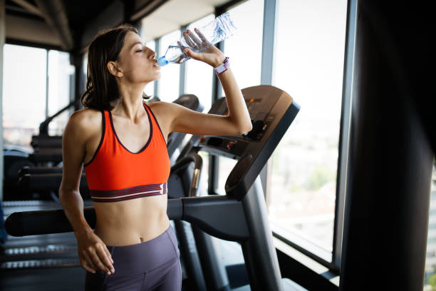 istock Refreshing after workout. Beautiful young woman drinking water to stay hydrate 1217801982