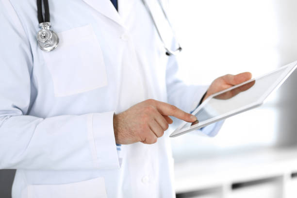 istock Doctor man using tablet computer for network research or virtual disease treatment, hands close-up. Perfect medical service in clinic. Modern medicine, medic data and healthcare concepts. Toned picture 1217803813