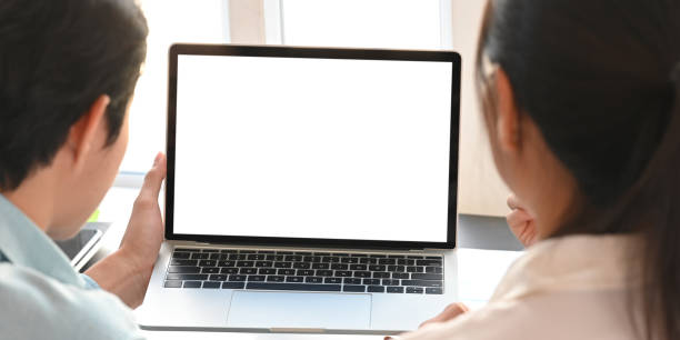 istock Behind shot of business people working together with white blank screen computer laptop while sitting together at black working desk over modern office as background. 1217807001