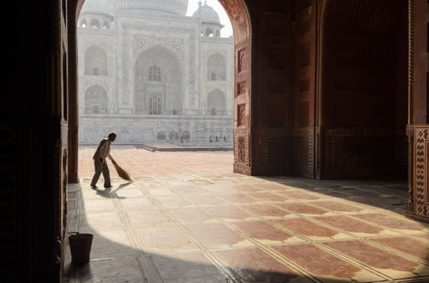 Mosque sweeper at the Taj Mahal, Agra, India Agra, India - 5 May 2015: A man sweeps the prayer room in the Taj Mahal main mosque before the Friday prayer, in Agra, India. The iconic Mughal mausoleum still serves as an active place of worship custodian silhouette stock pictures, royalty-free photos & images