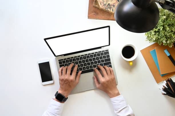 istock Top view image of businessman's hand typing on white blank screen computer laptop that putting on white working desk with office equipment. Orderly workplace concept. 1217807092
