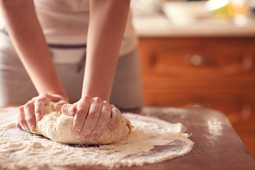 Female hands making dough for pizza