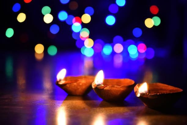 istock Three Oil lamp (Diya) Burning in the Dark with blurred colourful lights background 1217807980