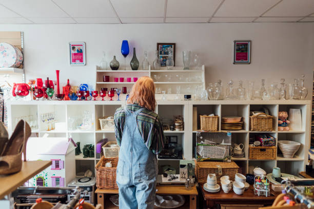 Shopping Second Hand Woman shopping at a thrift store. She is looking at miscellaneous items. second hand stock pictures, royalty-free photos & images