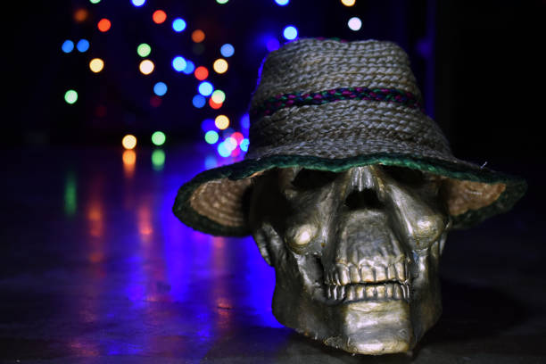 Human skeleton head or skull with top hat in the Dark with blurred colourful lights background (Halloween)