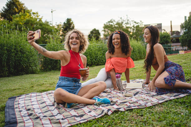 istock Cheerful young women taking a selfie while having a picnic at a park 1217809382