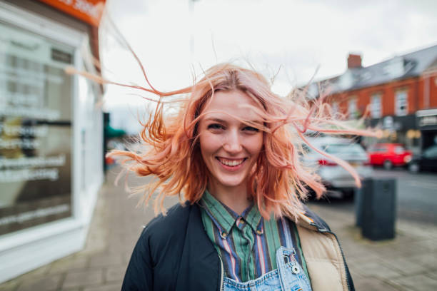 Having Fun Outdoors Woman standing outdoors looking away from the camera while her hair blows in the wind. pink hair stock pictures, royalty-free photos & images