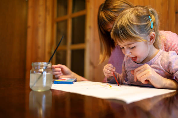 istock Excited girl painting while sitting in mom's lap 1217810203