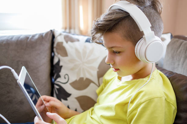 istock Kid with headphones holding digital tablet 1217811046
