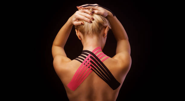 beautiful young woman with kinesiotape on her neck area after injury on black background - kinesio imagens e fotografias de stock