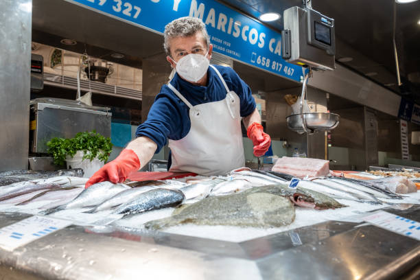 pescatore al mercato centrale durante la pandemia di coronavirus covid 19 a valencia, spagna - industrial fishing foto e immagini stock