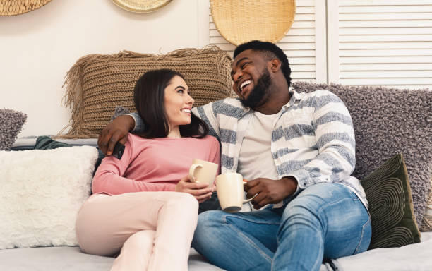 istock Man and woman sit on sofa and laugh 1217813770