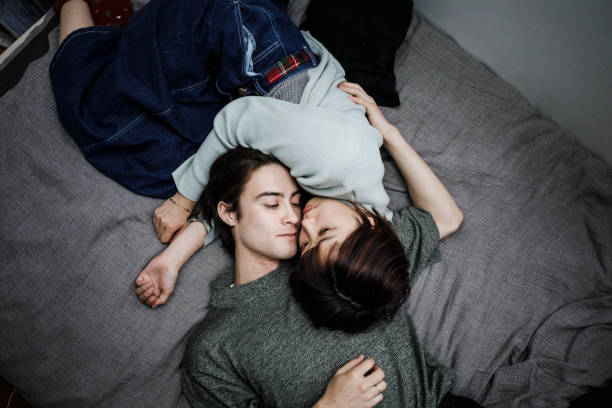 молодая пара, лежащая на кровати - couple affectionate relaxation high angle view стоковые фото и изображения