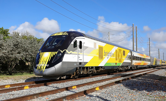 Fort Lauderdale, Florida USA - March 14, 2020:  Brightline high speed train now know as Virgin Trains USA traveling south towards Miami with power lines in the background.