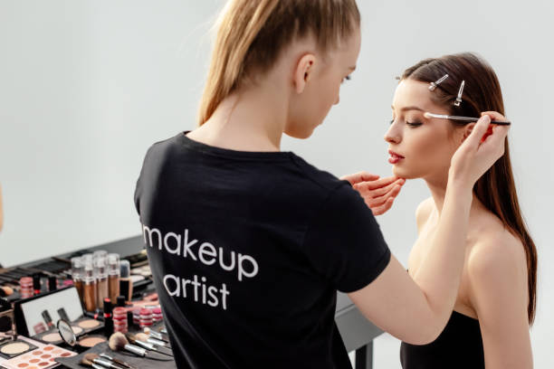 woman in black t-shirt with makeup artist lettering applying eye shadow on model woman in black t-shirt with makeup artist lettering applying eye shadow on model makeup artist stock pictures, royalty-free photos & images