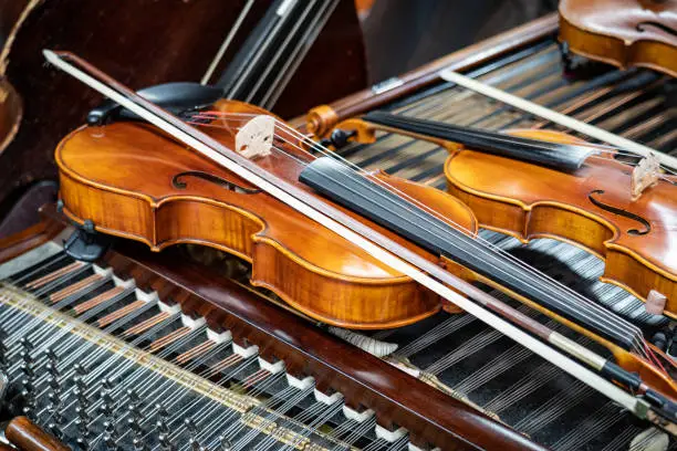 Photo of Antique violin and violin bow lying on dulcimer. Close up a violin instrument and cymbal before a concert. Music concept background