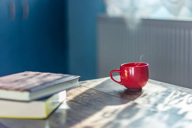 istock Stack of books and a cup of hot drinks on a table by the window 1217815493