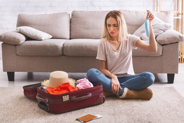 istock Woman looks sadly at suitcase with clothes 1217815638