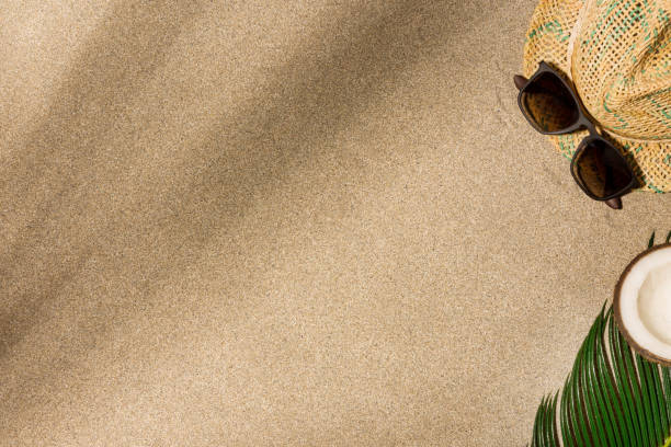 istock Hat and sunglasses on sand background. Harsh light with shadows. 1217816015