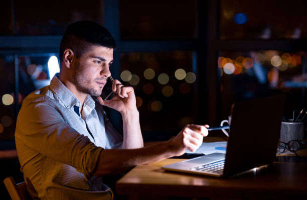 istock Businessman Talking On Phone Sitting In Office At Night 1217816052
