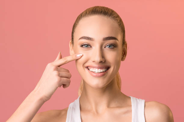 istock Smiling girl touching face applying facial cream posing in studio 1217816145