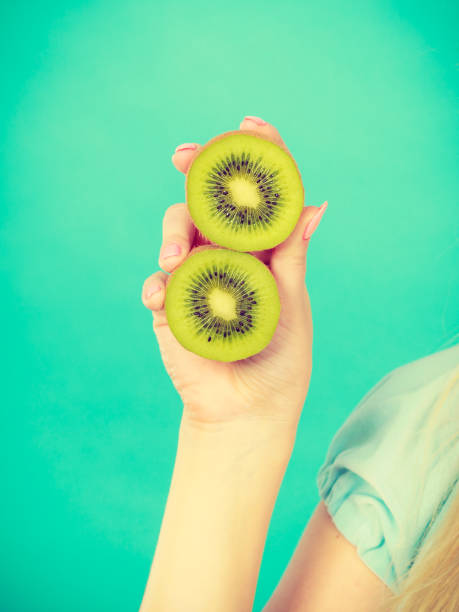 istock Woman holding green kiwi fruit 1217816317