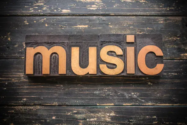 The word "MUSIC" written in vintage wood letterpress type on a vintage rustic background.