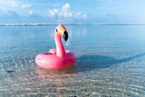 istock Inflatable pink flamingo floating at transparent turquoise sea. Blue sky with few clouds on the background. 1217817607
