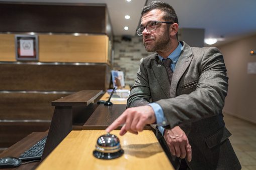 Businessman arriving in the hotel and ringing at the reception desk