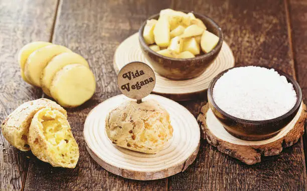 Vegan cheese bread, made without animal products, with ingredients on the side, tapioca and potatoes. Wooden sign with inscription: Vegan life.