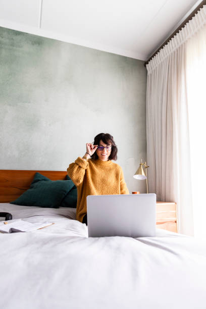 istock Woman puts on spectacles while using laptop in bedroom 1217819004