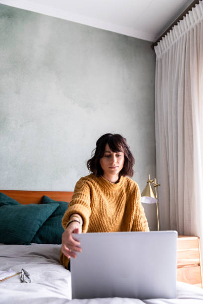 istock Woman sits on bed working from home 1217819105