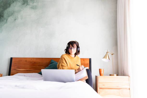 istock Wide shot woman taking notes during online meeting while working at home 1217819141