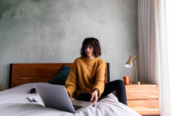 istock Woman sits on bed ready to start working form home 1217819161