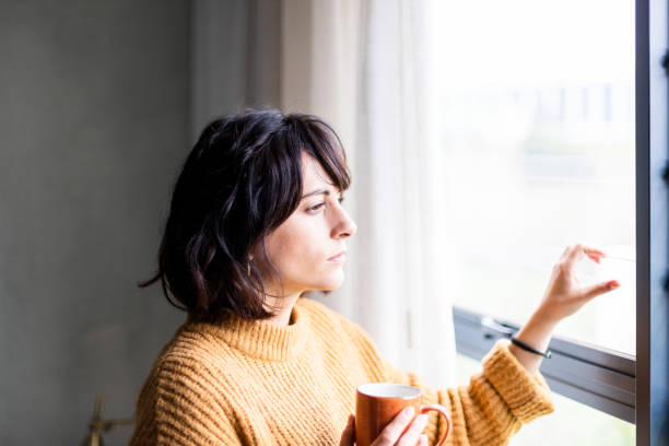istock Serious young woman looking out the window during lockdown 1217819845