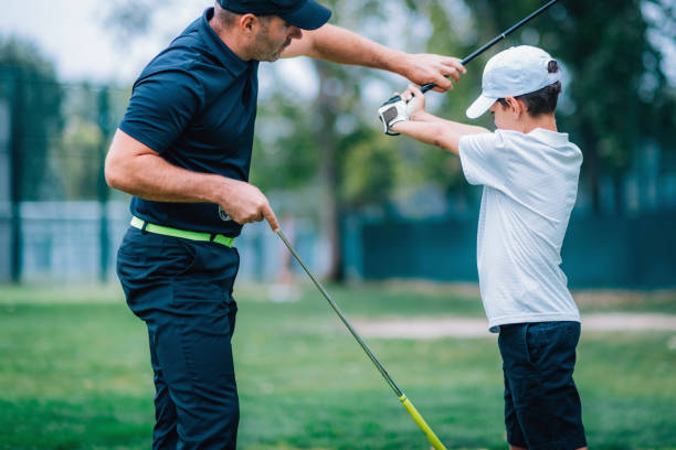 golf – trening osobisty. instruktor golfa nauczania młody chłopiec, jak grać w golfa. - golf green practicing sports training zdjęcia i obrazy z banku zdjęć