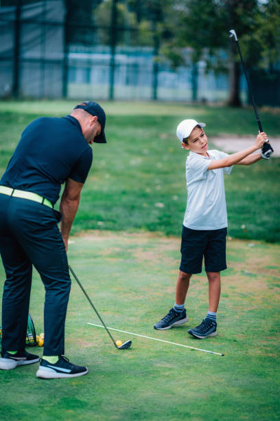 golf – trening osobisty. instruktor golfa nauczania młody chłopiec, jak grać w golfa. - golf green practicing sports training zdjęcia i obrazy z banku zdjęć