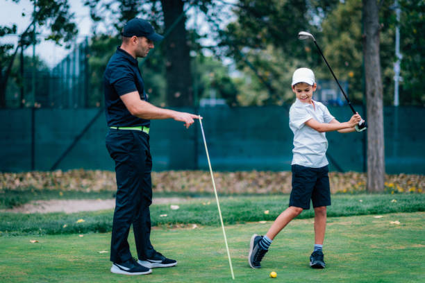 golfe – treinamento pessoal. instrutor de golfe ensinando o garoto a jogar golfe. - golf green practicing sports training - fotografias e filmes do acervo