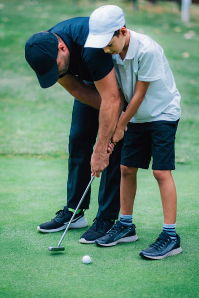 golfe colocando treinamento. instrutor de golfe com garoto praticando no verde de colocar - golf green practicing sports training - fotografias e filmes do acervo