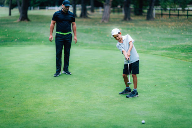 golfe colocando treinamento. instrutor de golfe com garoto praticando no verde de colocar - golf green practicing sports training - fotografias e filmes do acervo